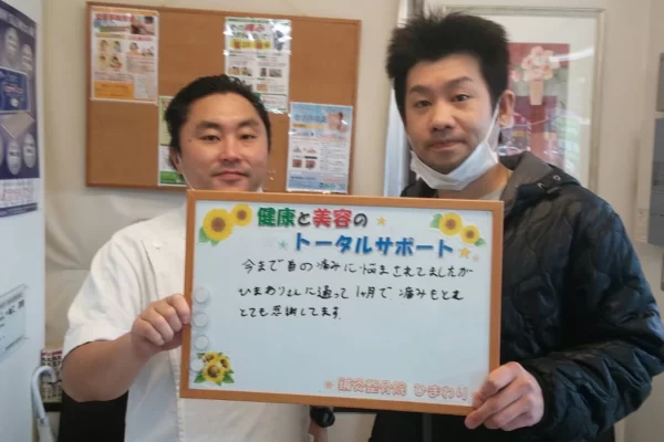 患者様の声:寝違え(首の痛み)が1ヶ月で改善|鍼灸整骨院ひまわり北久里浜院(横須賀市) 横須賀市の鍼灸整骨院ひまわり北久里浜院で、寝違え(首の痛み)の施術を受け、「1ヶ月で痛みもとれとても感謝してます」と書かれたボードを掲げる施術者と患者様の様子。