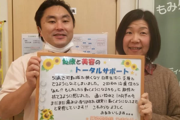 患者様の声:四十肩・五十肩(50肩)が改善|鍼灸整骨院ひまわり北久里浜院(横須賀市) 横須賀市の鍼灸整骨院ひまわり北久里浜院で、四十肩・五十肩(50肩)の施術を受け、「確実に動くようになってきた」と書かれたボードを掲げる施術者と患者様の様子。