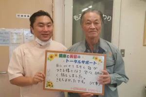 横須賀市の鍼灸整骨院ひまわり北久里浜院で、坐骨神経痛の施術を受け、「対応も良くきもちよかった」と書かれたボードを掲げる施術者と患者様の様子。