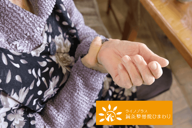 花柄の服を着た人物が、片方の手で反対側の手首の内側を抑えている様子。右下には「ライフプラス 鍼灸整骨院 ひまわり」のロゴ。 