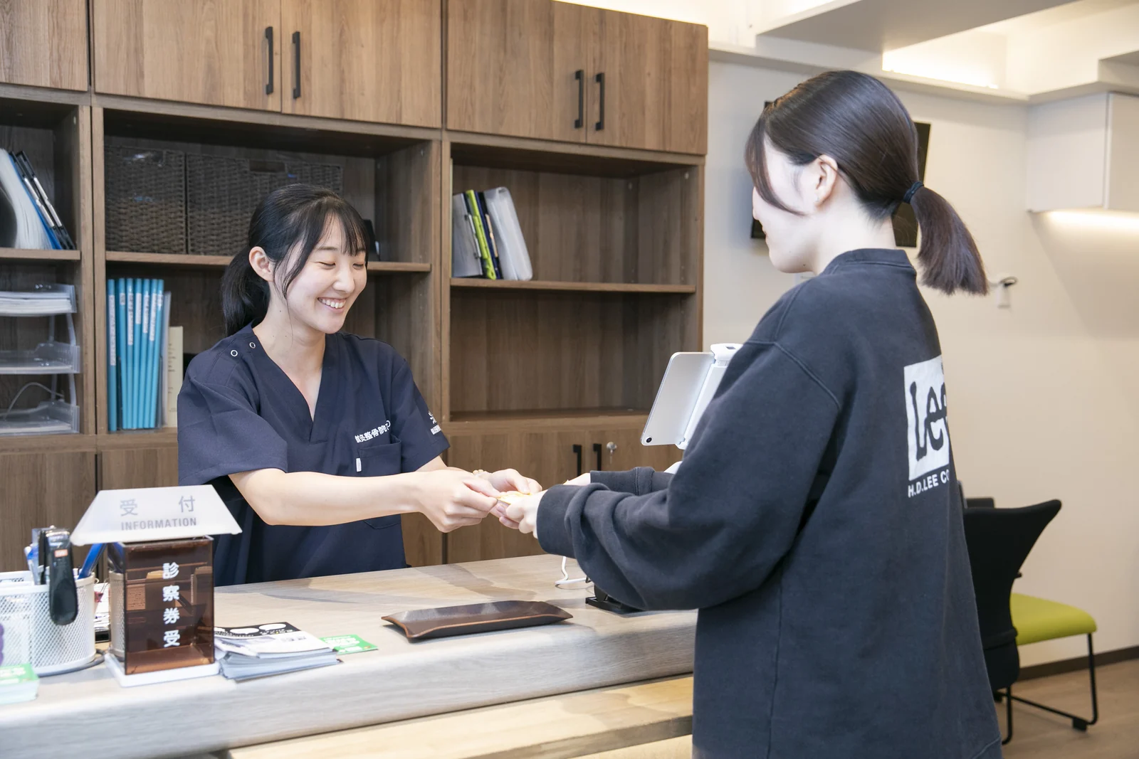 鍼灸整骨院ひまわりの受付でスタッフが来院者に対応する様子 鍼灸整骨院ひまわりの受付でスタッフが来院者に対応する様子