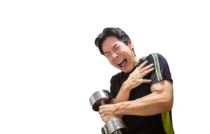 ダンベルを持ち上げた際に肩を押さえて激痛を訴える男性。回旋腱板損傷の痛みを表現したイメージ。