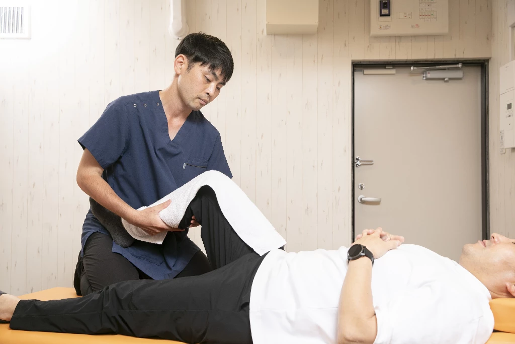 ふくらはぎの肉離れ(こむら返り)の施術・リハビリ|横須賀市の鍼灸整骨院ひまわり 横須賀市の鍼灸整骨院ひまわり(北久里浜院・衣笠院)で行う、ふくらはぎの肉離れへの手技施術。施術者が患者様の膝や足首の可動域を検査し、リハビリを行っている様子。