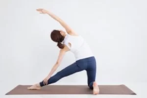 横須賀市の鍼灸整骨院ひまわり（北久里浜院・衣笠院）で行う、ハムストリングス肉離れ（もも裏の痛み）の再発予防ストレッチ。女性がヨガマットの上で体側と下半身を伸ばしている様子。