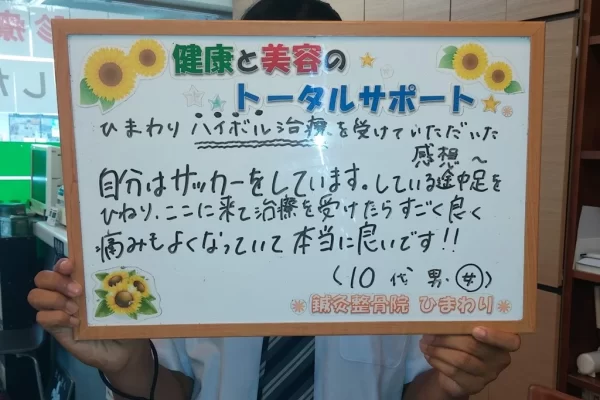 横須賀市の鍼灸整骨院ひまわり北久里浜院で、足関節捻挫（サッカー）のハイボルテージ施術を受け、「痛みもよくなっていて本当に良いです!!」と書かれたボードを掲げる患者様の様子。