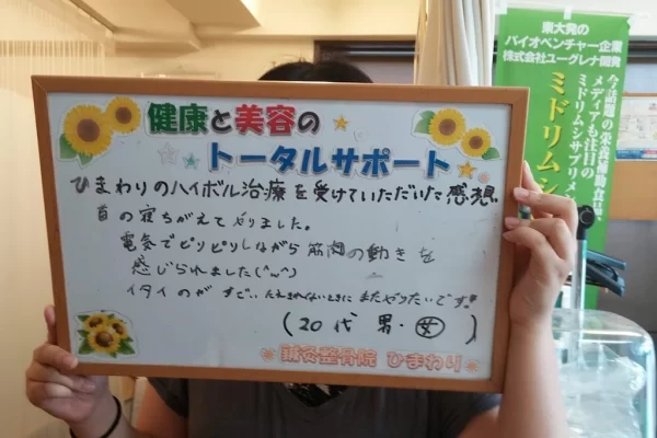 患者様の声:寝違え(首のズレ)がハイボルテージ施術で改善|鍼灸整骨院ひまわり北久里浜院(横須賀市) 横須賀市の鍼灸整骨院ひまわり北久里浜院で、寝違え(首のズレ)のハイボルテージ施術を受け、「首の骨がずれてもどりました」と書かれたボードを掲げる患者様の様子。