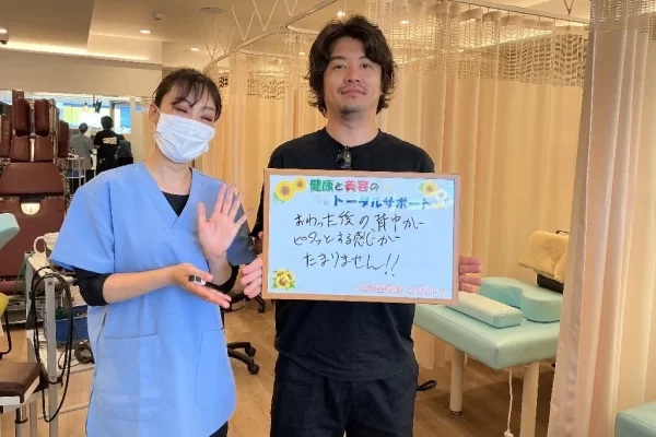 横須賀市の鍼灸整骨院ひまわり北久里浜院で、猫背矯正プログラムを受け、「おわった後の背中がシャキッとする感じがたまりません!!」と書かれたボードを掲げる施術者と患者様の様子。