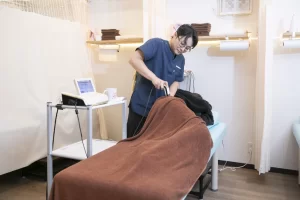 横須賀市の鍼灸整骨院ひまわりで、ぎっくり腰の根本原因である骨格の歪みを改善するためにハイボルテージ施術と骨格矯正を行う様子