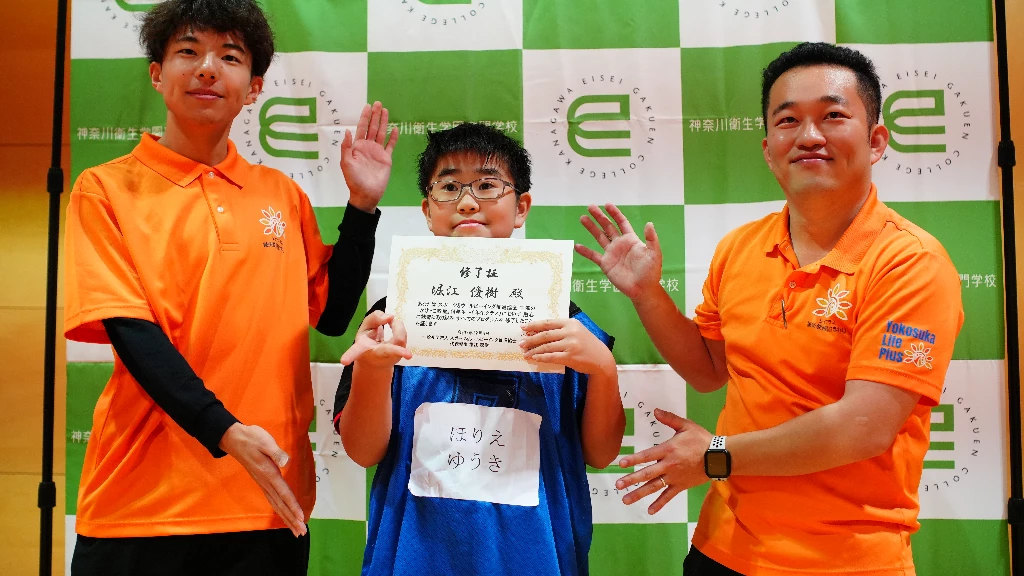 横須賀市のかけっこ教室で、修了証を手にした参加者とスタッフが並んで記念撮影する様子