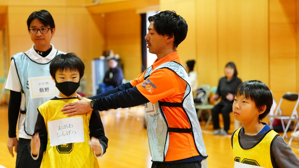 横須賀市のかけっこ教室で、スタッフが参加者の姿勢を確認しながら動き方を指導する様子